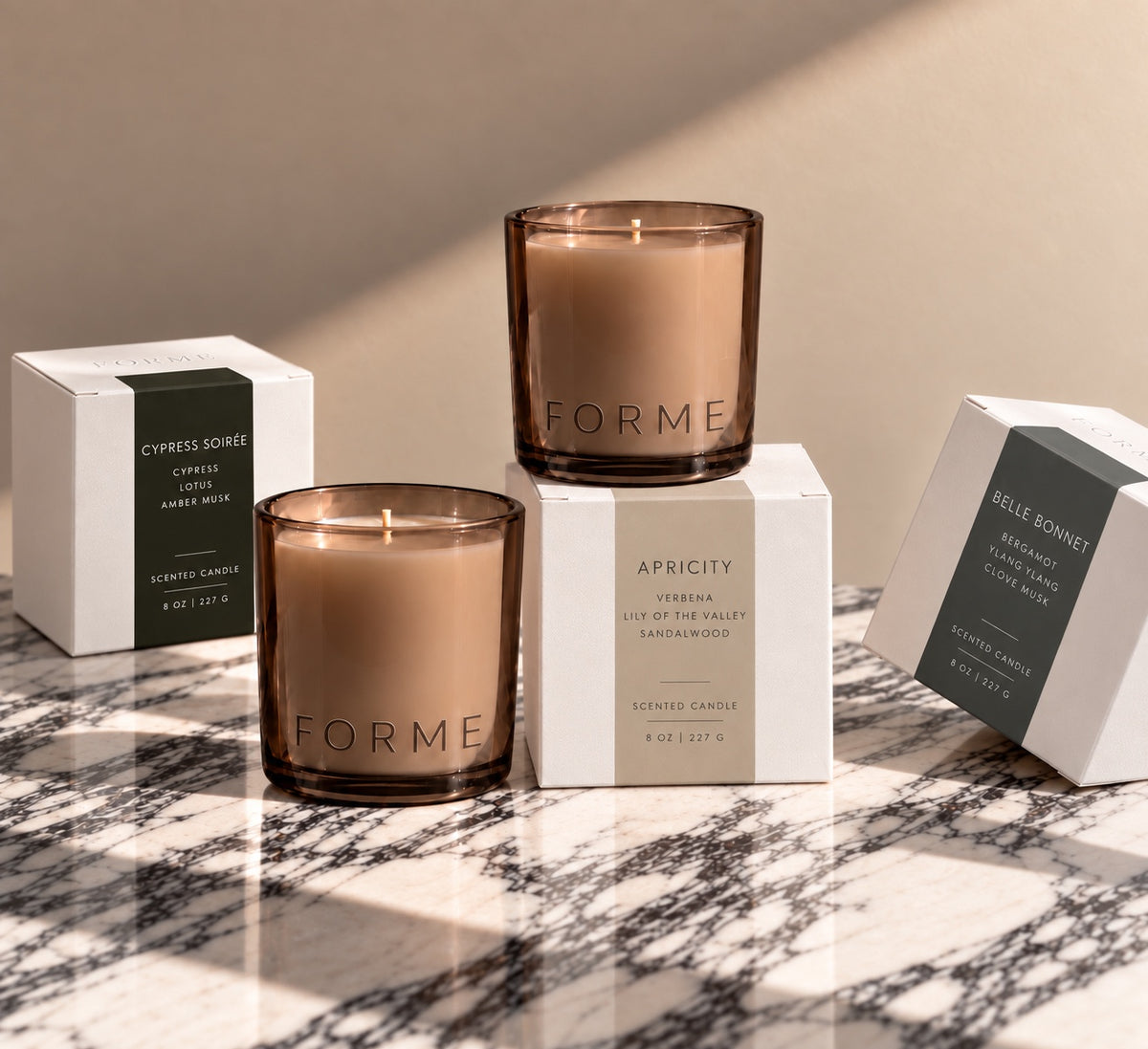 FORME 8 oz candles with packaging on sunlit marble